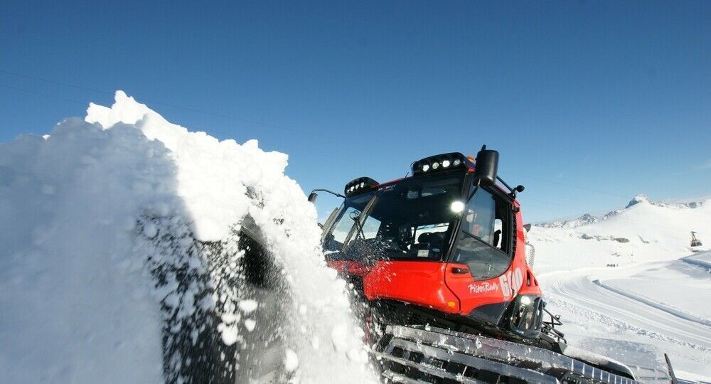 PistenBully 600 Polar schiebt Schnee mit dem Schild.