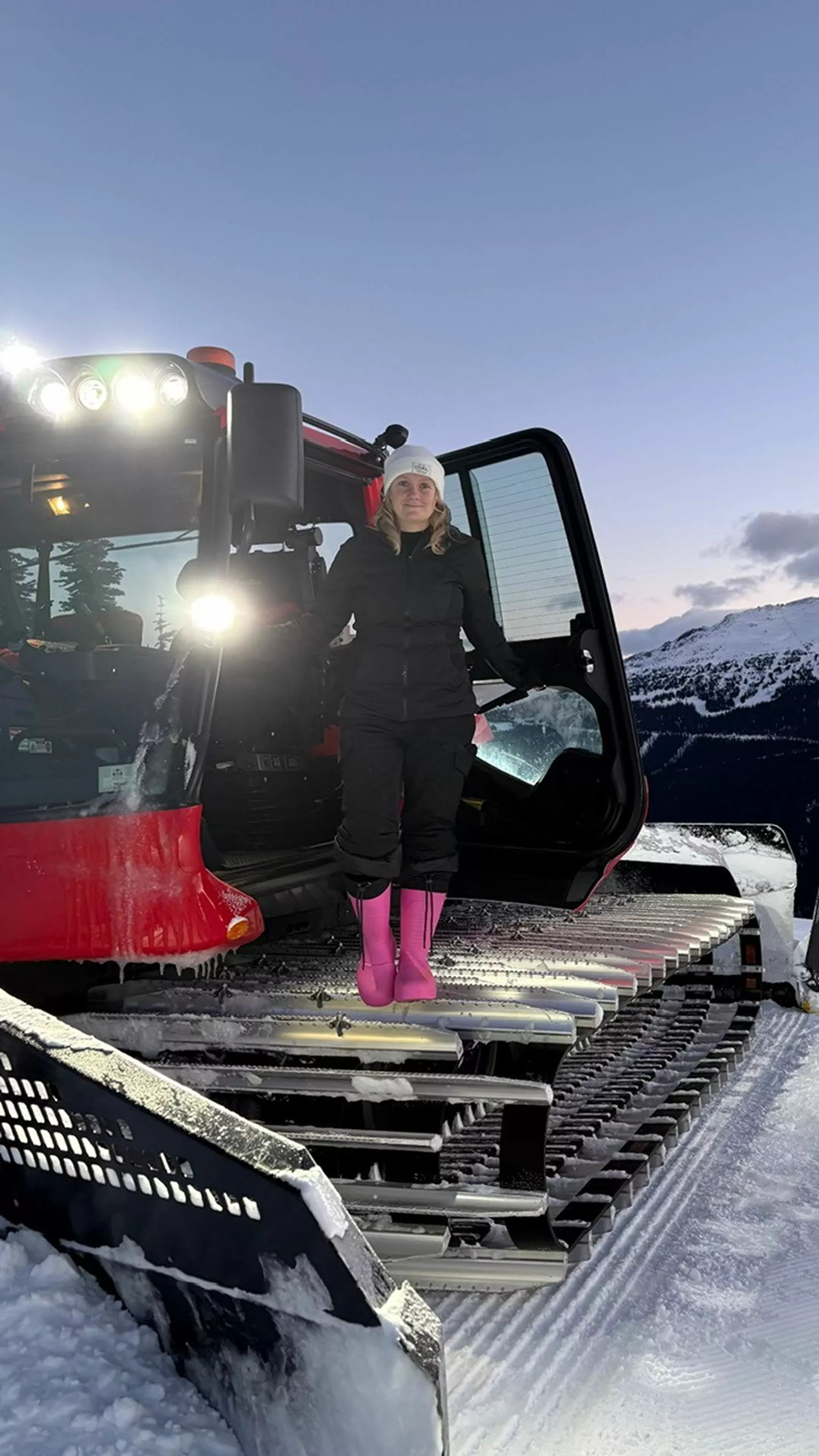 Samantha Bird standing on the tracks of her PistenBully